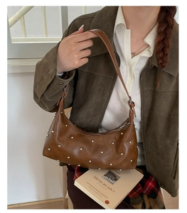 Detail view of dark brown stud-embellished shoulder bag with silver rivet hardware accents