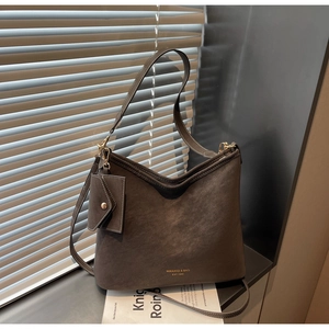 Close-up of brown faux leather tote bag texture with gold lettering and small coin purse