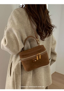 Détail du sac boîte en daim marron avec ferrures dorées et bandoulière réglable
