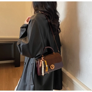 Detail of burgundy and brown crossbody bag with colorful beads and gold twist lock