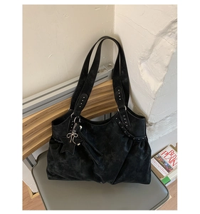 Detail of black suede tote bag with silver rivets and star-shaped leather pendant