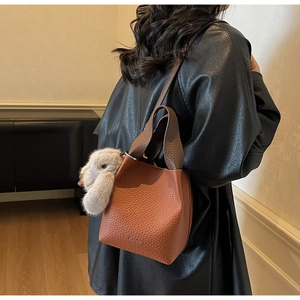 Brown litchi grain leather bucket bag with cute plush bunny charm and embossed logo detail