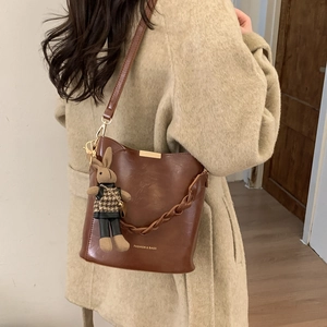 Brown leather bucket bag detail with adjustable strap and cute knit rabbit charm