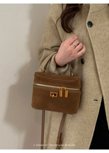 Détail du mini sac boîte en daim marron avec fermetures dorées et bandoulière