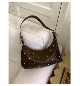 Detail of dark brown crescent shoulder bag with silver rivet studs on soft leather