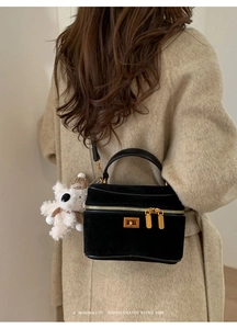 Détail du sac à bandoulière en velours noir avec boucle dorée et breloque petit ours