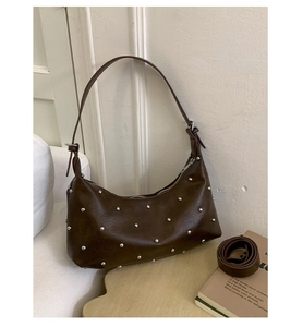 Detailed macro view of dark brown hobo bag with silver rivets and extra strap