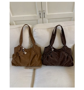 Detail view of large faux suede tote bags in camel and brown with star charm and silver studs