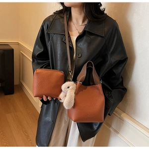 Detail of caramel bucket bag with lychee texture and cute plush rabbit charm