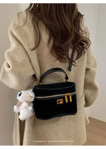 Détail d'un sac boîte noir en daim avec ferrures dorées et breloque mouton en peluche