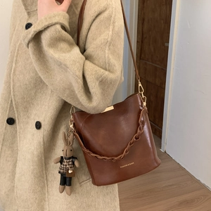 Detail of vintage brown leather bucket bag with gold hardware and plush rabbit charm
