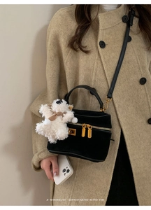 Détail du sac boîte en daim noir avec ferrures dorées et breloque ours en peluche