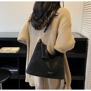 Detail of black leather tote bag with white contrast stitching and a small zipper pouch
