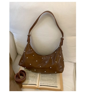 Detail of dark brown hobo bag with silver studs on an open book background