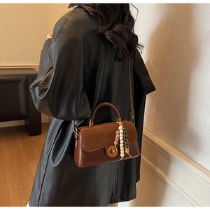 Brown vintage handbag detail with golden twist lock and ethnic wooden bead charms