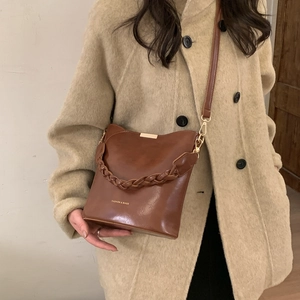 Caramel retro bucket bag with woven handle shown on model in a beige coat for daily wear