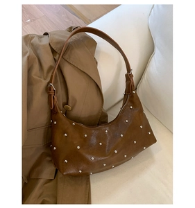 Detailed macro view of dark brown crescent bag with silver rivets and vintage leather texture