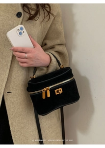 Détail du sac boîte rétro en daim noir avec doubles fermetures dorées et fine bandoulière