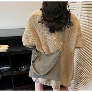 Close-up of sage green suede crossbody bag with matching accessory pouch and strap