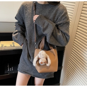 Brown litchi leather bucket bag featuring a cute plush long-eared rabbit charm accessory