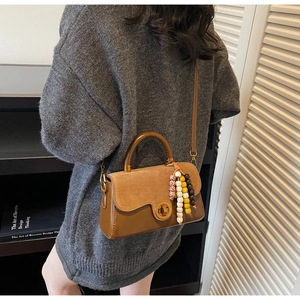 Detail of vintage brown patchwork handbag featuring metal lock and colorful bead tassel