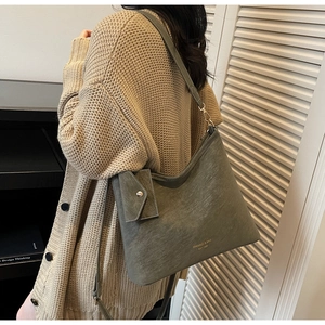 Detail of gray-green matte tote bag with gold logo and small envelope charm accessory