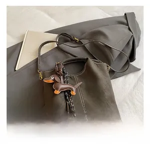 Detail of matte green shoulder bag with white stitching and dog-shaped leather charm