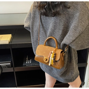 Brown vintage leather handbag detail with retro metal lock and decorative beaded pendant