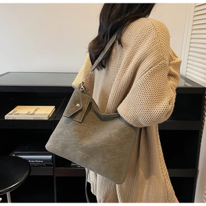 Detail of gray-green tote bag with gold logo and matching coin purse on shoulder