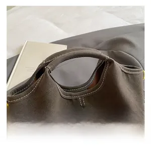 Detailed close-up of dark brown suede handbag handle with contrast white stitching