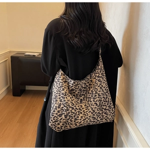 Vue arrière d'un mannequin portant un grand sac cabas léopard avec un manteau noir