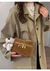 Détail du sac boîte en daim marron avec ferrures dorées et breloque chien en peluche