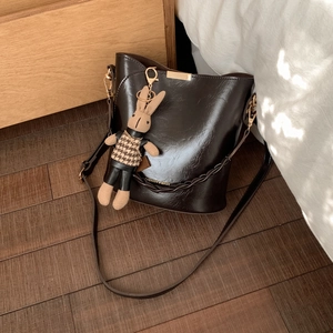 Detail of dark brown faux leather bucket bag with fashion text and rabbit charm