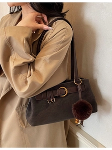 Retro dark brown leather shoulder bag with buckle detail and plush charm on trench coat