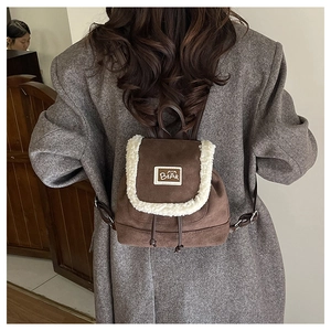Detail showing plush trim and bear logo patch on a brown faux suede mini backpack