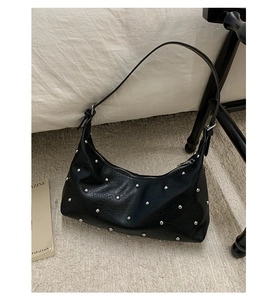 Detailed view of black faux leather hobo bag with silver metal studs and crescent shape