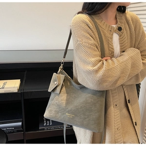 Close-up of gray-green tote bag set on beige sweater with texture detail