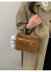 Gros plan du sac boîte en daim marron avec zip doré et breloque ours en peluche