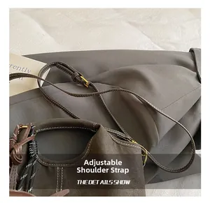 Detail of adjustable thin shoulder strap with gold metal buckle on dark brown bucket bag