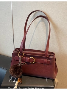 Vintage burgundy matte leather handbag with metal buckle and brown fur ball charm
