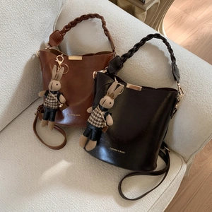 Detail of vintage bucket bags in brown and black leather with woven handles and rabbit charm