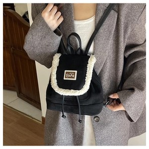 Detail of mini black backpack with white faux fur trim and brown leather bear patch