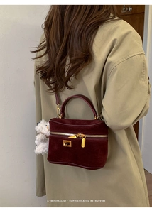 Détail du sac boîte en daim bordeaux avec fermoir doré et charm d'ours en peluche