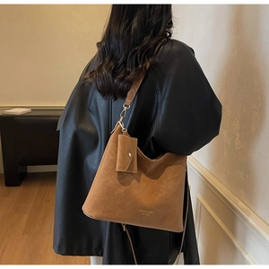 Close-up of vintage brown suede tote bag with side pouch and gold brand lettering