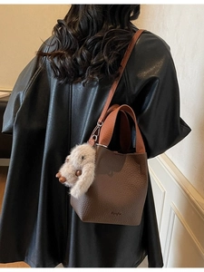 Deep brown pebble leather bucket bag with orange handle and cute plush charm pendant