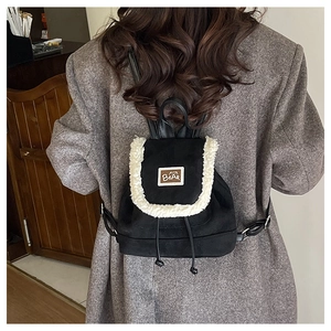 Close-up of a mini black suede backpack with white faux fur trim and bear logo patch