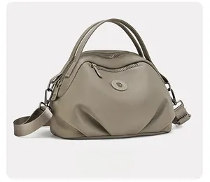 Side view of taupe crossbody bag showing nylon texture and metal hardware details