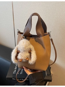 Brown lychee leather bucket bag with plush rabbit charm and crossbody strap