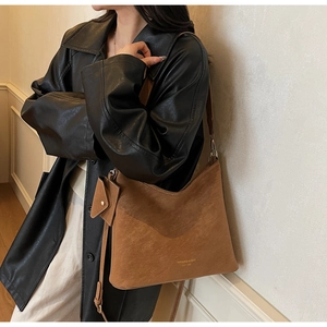 Detail of dark brown suede tote bag featuring adjustable strap and mini pouch pendant