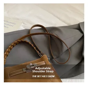 Detail shot of vintage brown leather bucket bag with metal lock and adjustable shoulder strap
